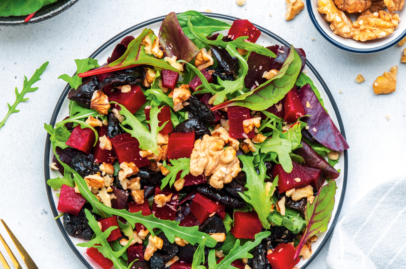 Overhead shot of an arugula and beet salad with walnuts and spring mix.